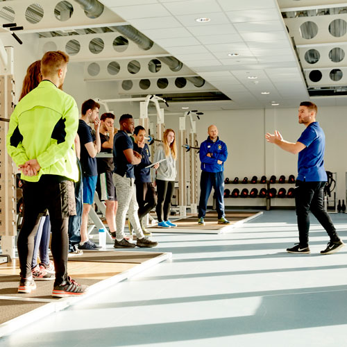 Students stood in sports hall listening to tutor