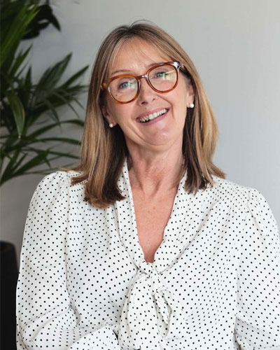 Woman with glasses and medium brown hair smiling to camera