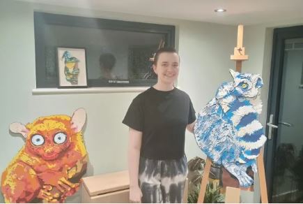 Alley Scout standing next to their illustrated characters.