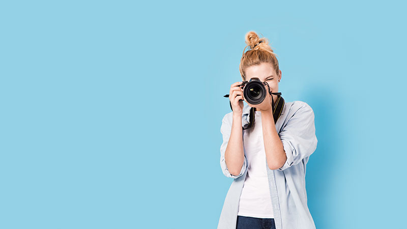 Person taking photograph in front of blue wall