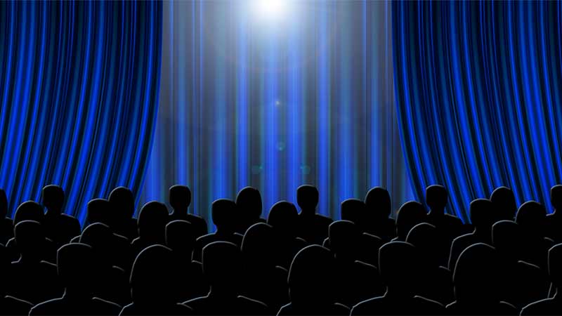 Back of audience waiting for curtain to raise in theatre