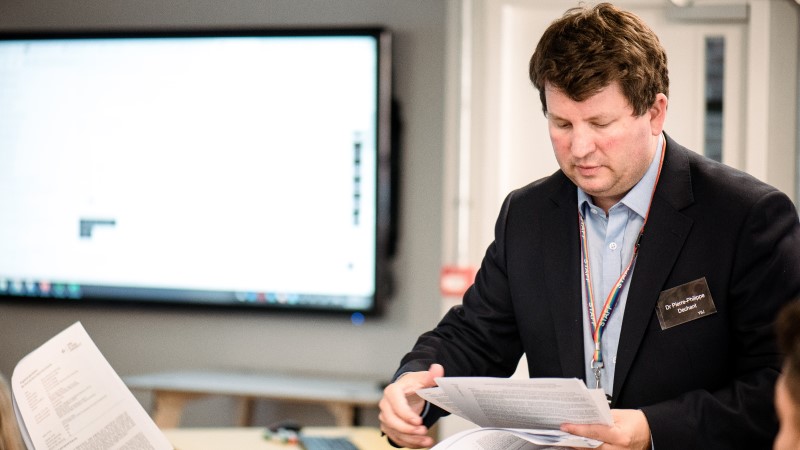 A smartly dressed man working in front of a large computer screen