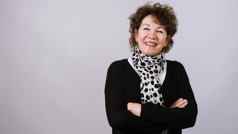 A woman in a black top and patterned scarf smiling at the camera