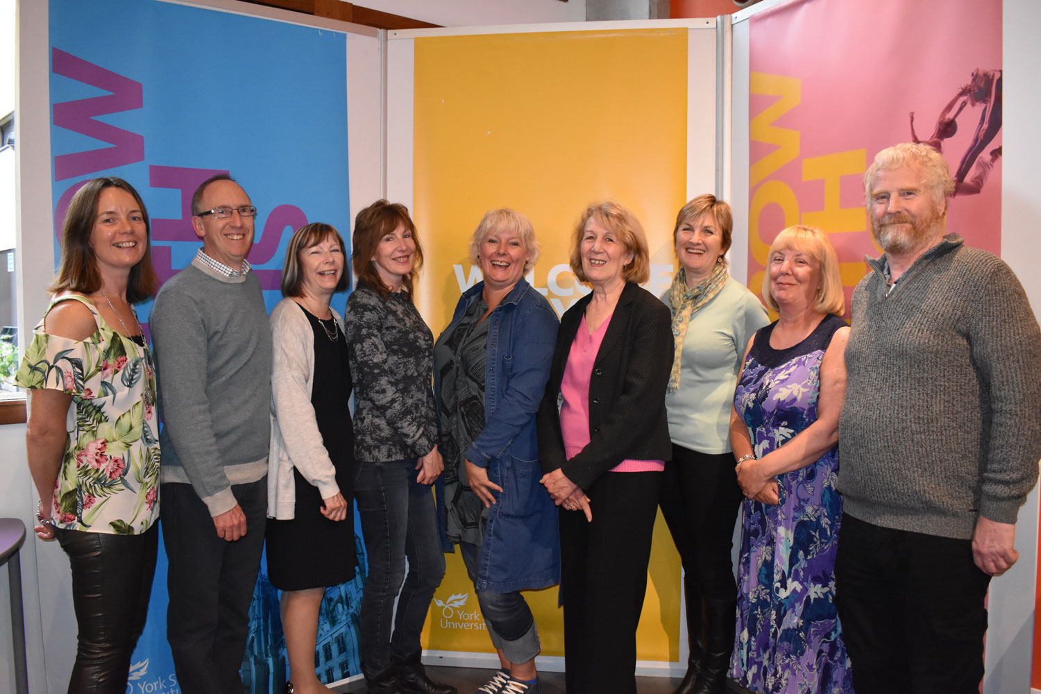 9 people standing in front of coloured background