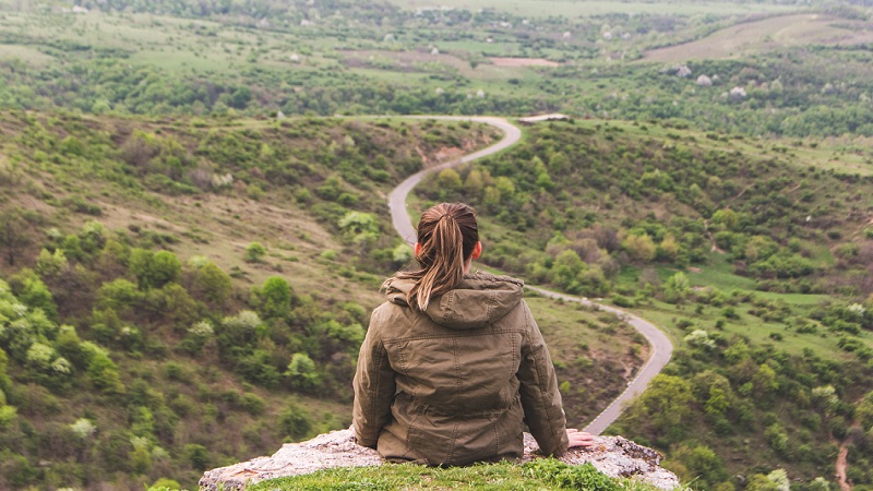 Woman looking a long road from a high hill