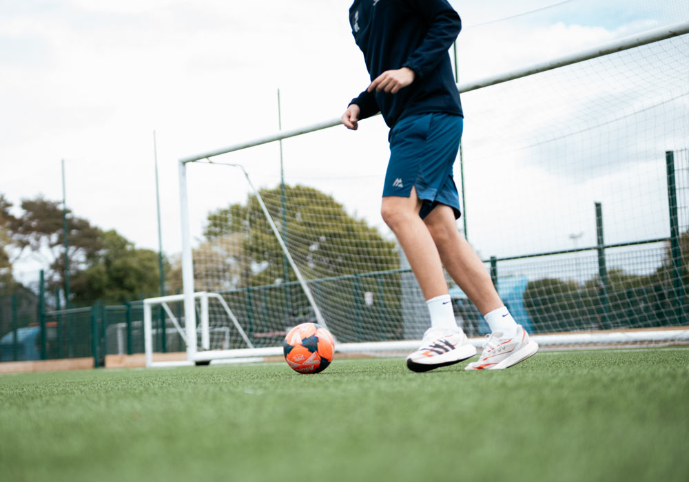 An individual preparing to kick a football with a goalpost behind