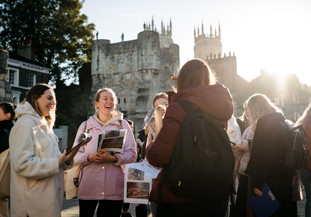 A group of students chatting in York with Bootham Bar and York Minster behind
