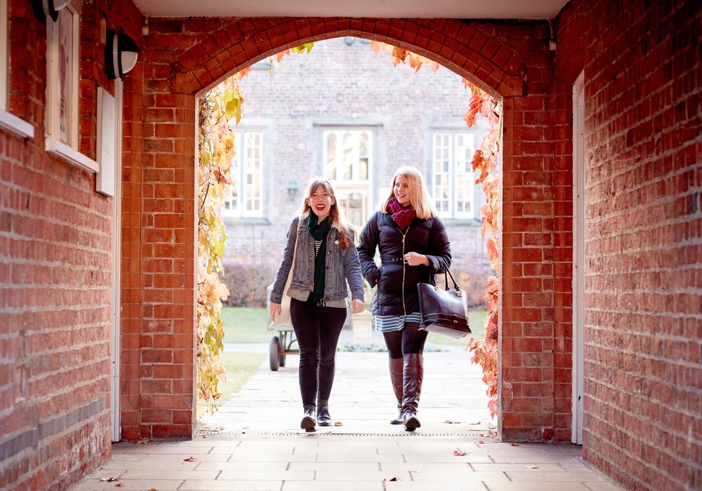 Two students walking through an archway.