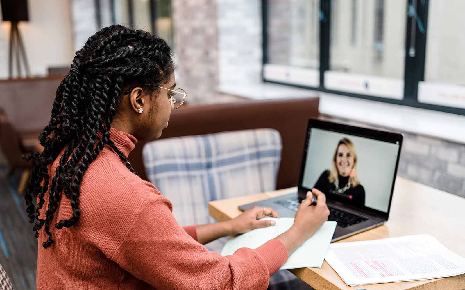 A student makes notes whilst on a video call with a lecturer