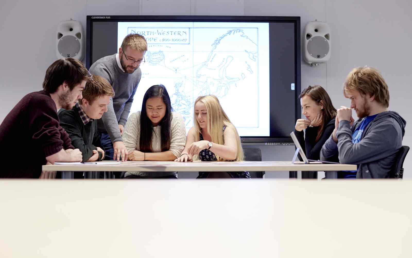 A lecturer working with a group of students in a seminar