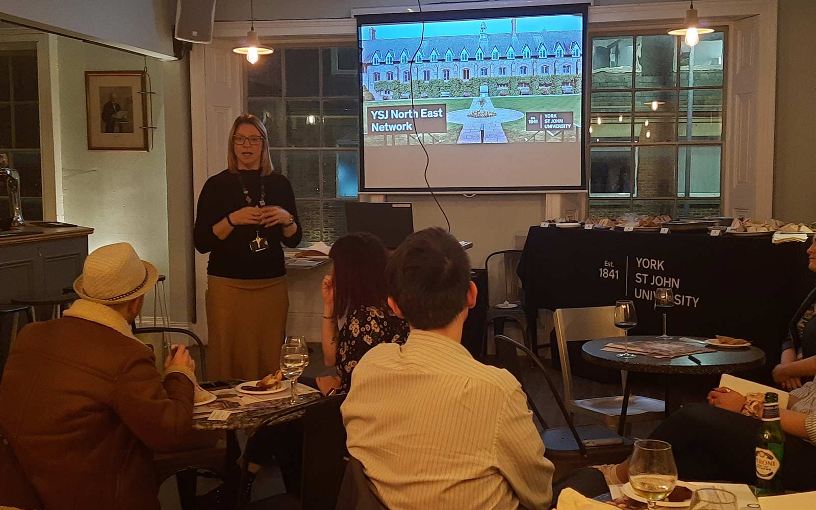 Member of Alumni team addressing seated guests at Alumni network event