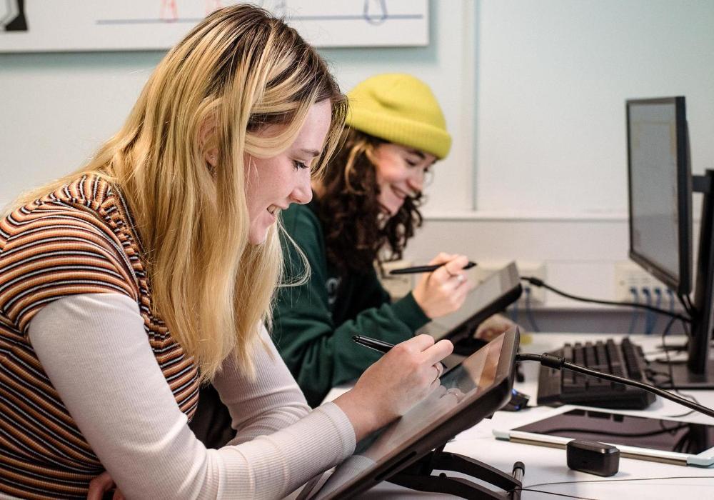 Two animation students work side by side sketching on tablets