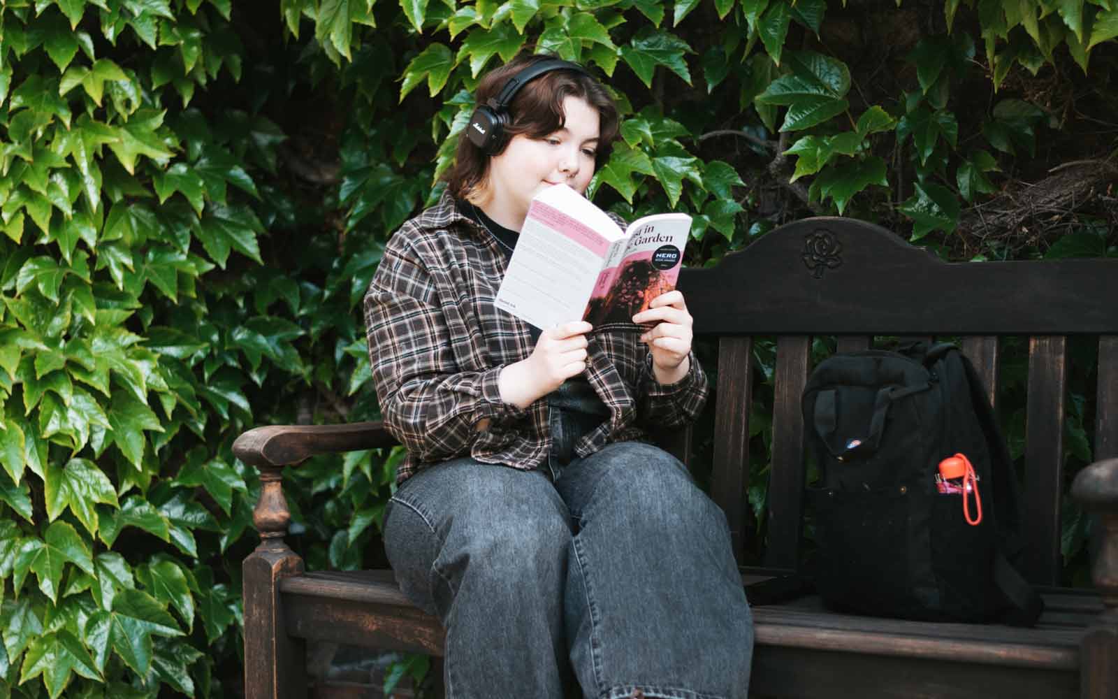 A student reading a book while sitting on a bench.