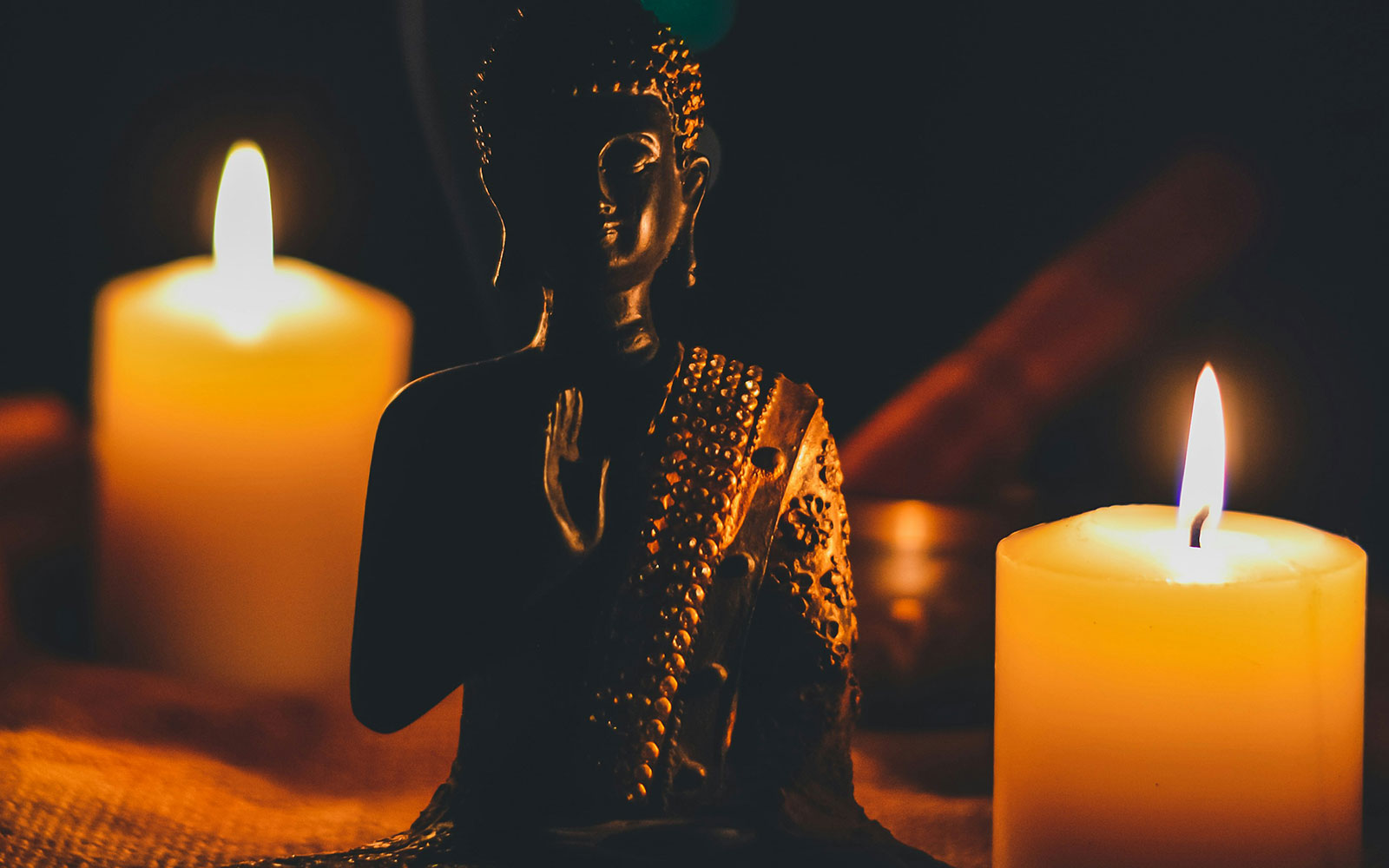 Sitting Buddha besides candles