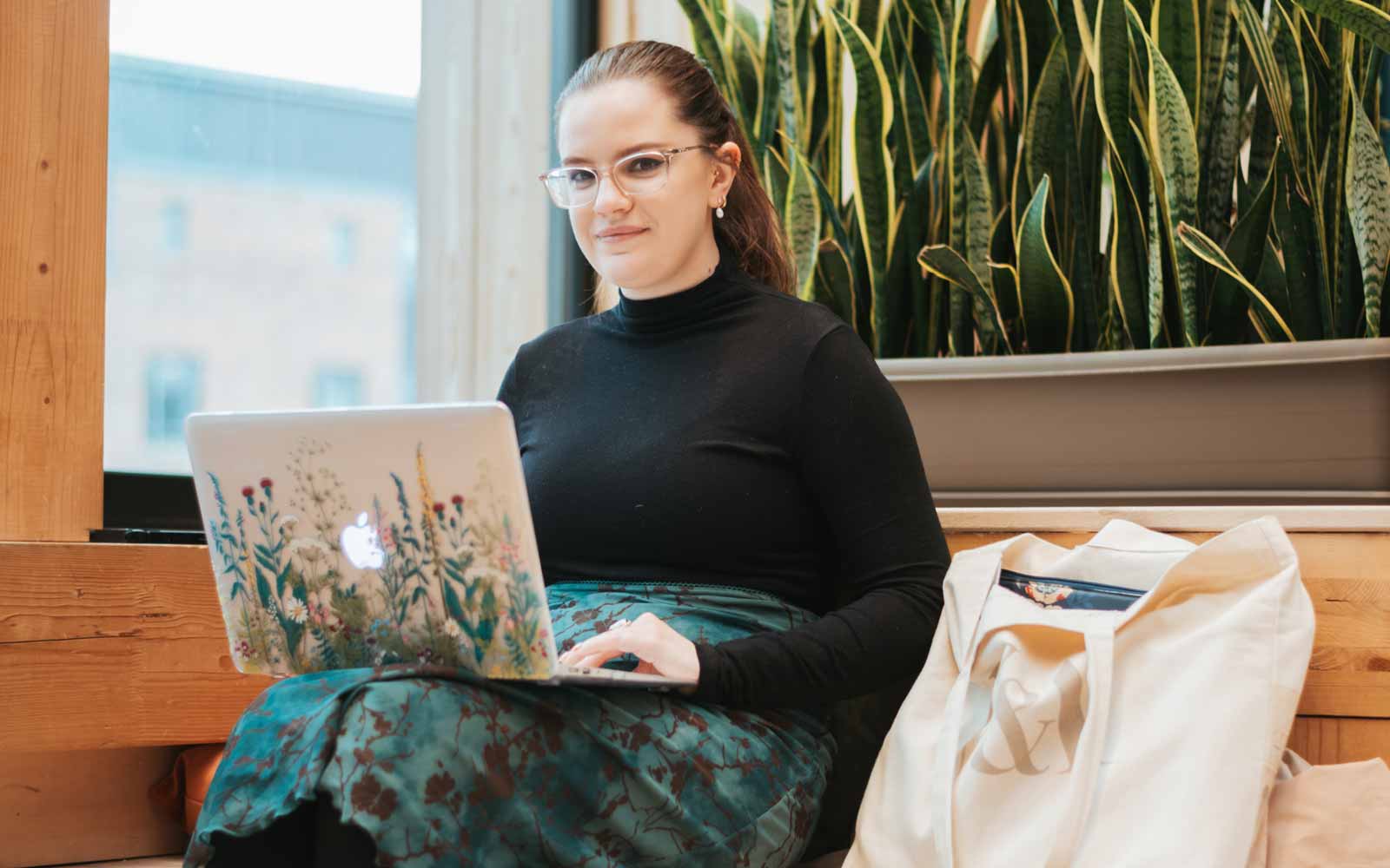 A student sitting down with a laptop on her knee.