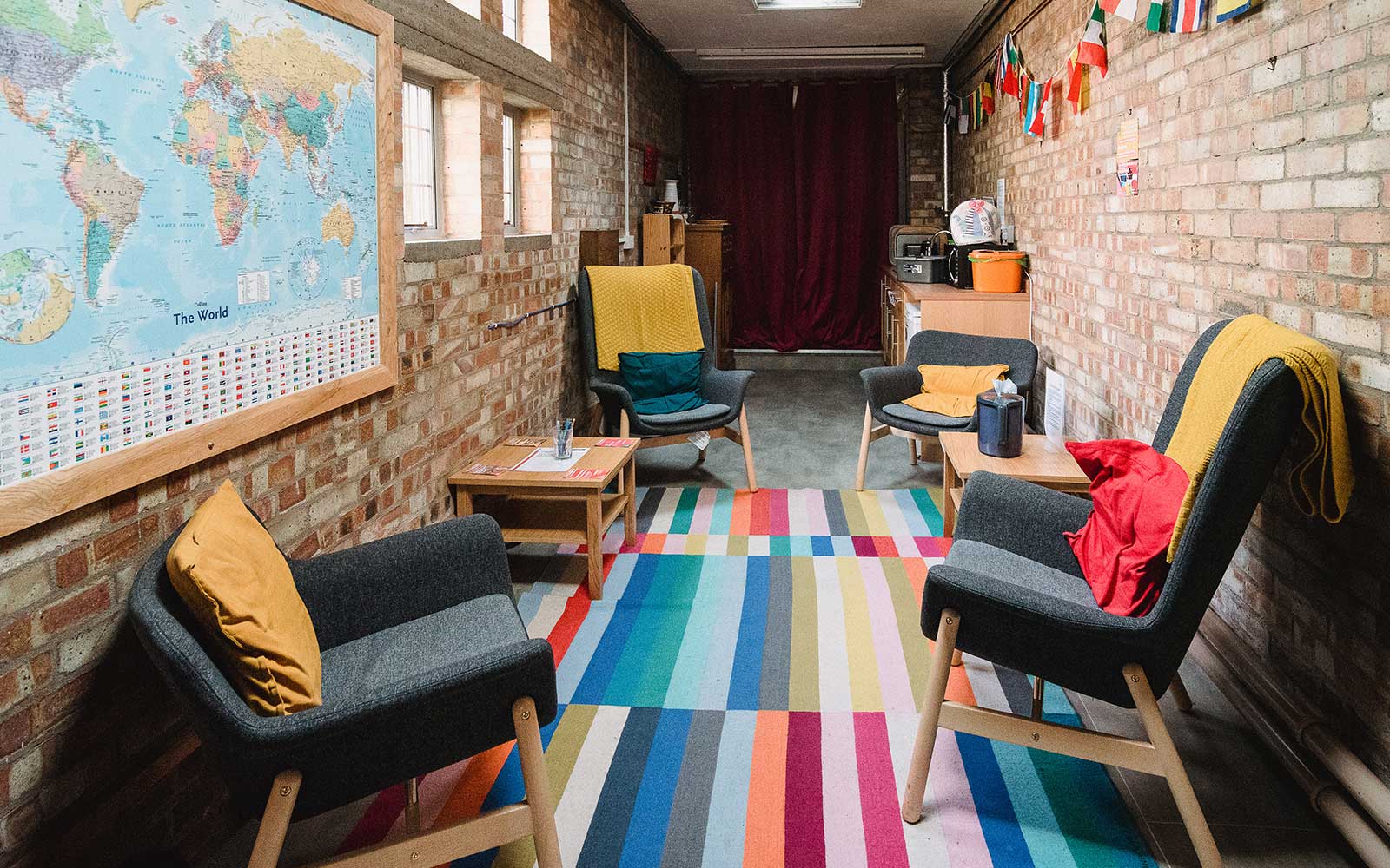 Chairs and a coffee table in the Chapel Kitchen, decorated with a stripy rug and world flags
