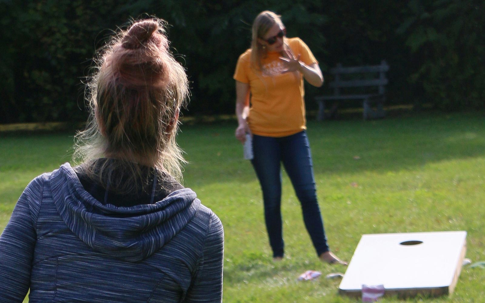 Two people playing cornhole garden game