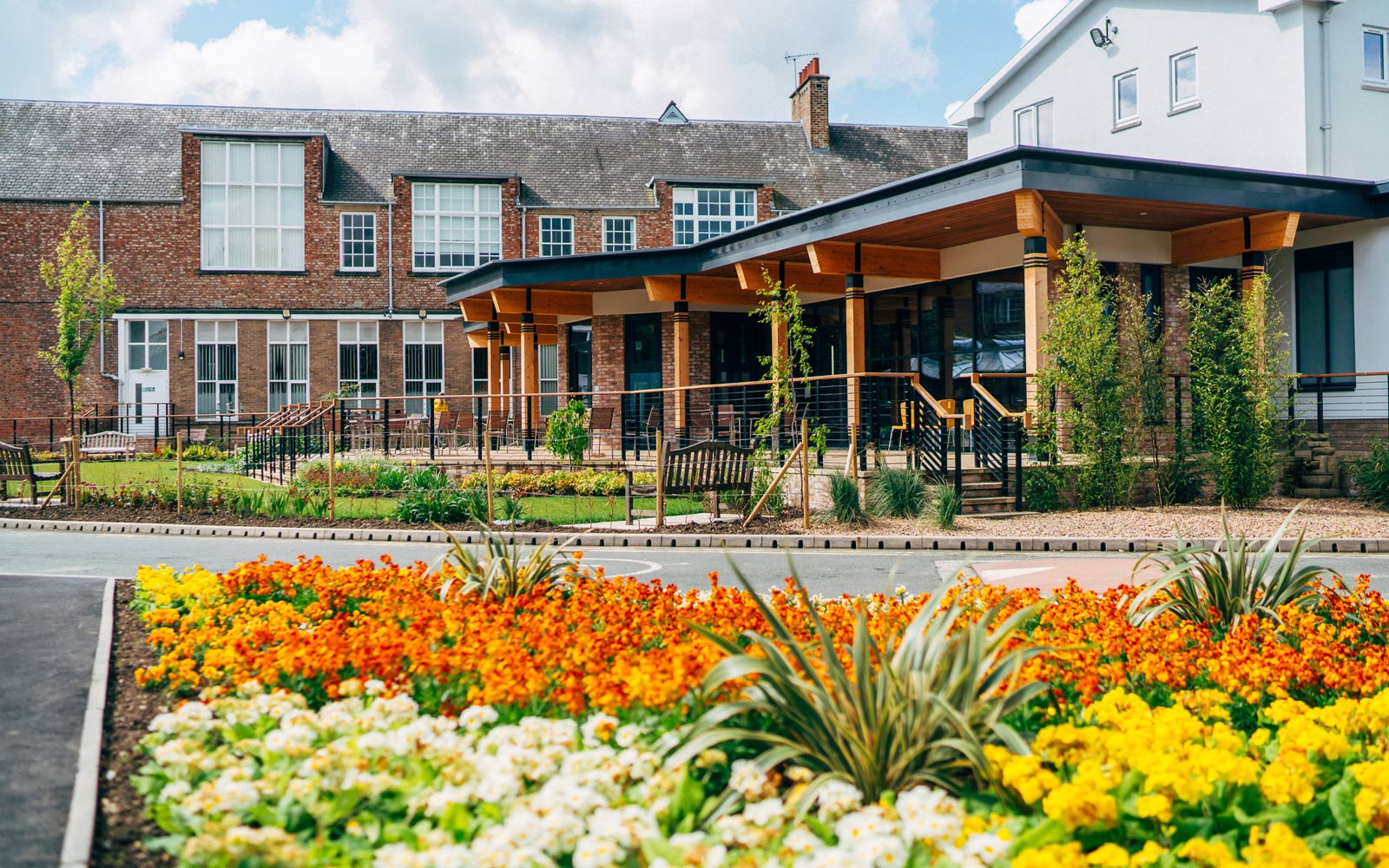 View of the dining room building on campus with orange and yellow flowers in the foreground
