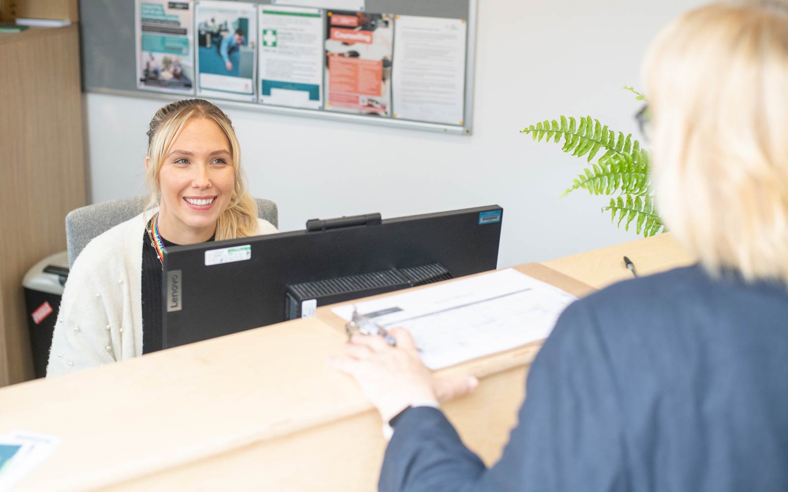Individual at reception desk greeting someone.