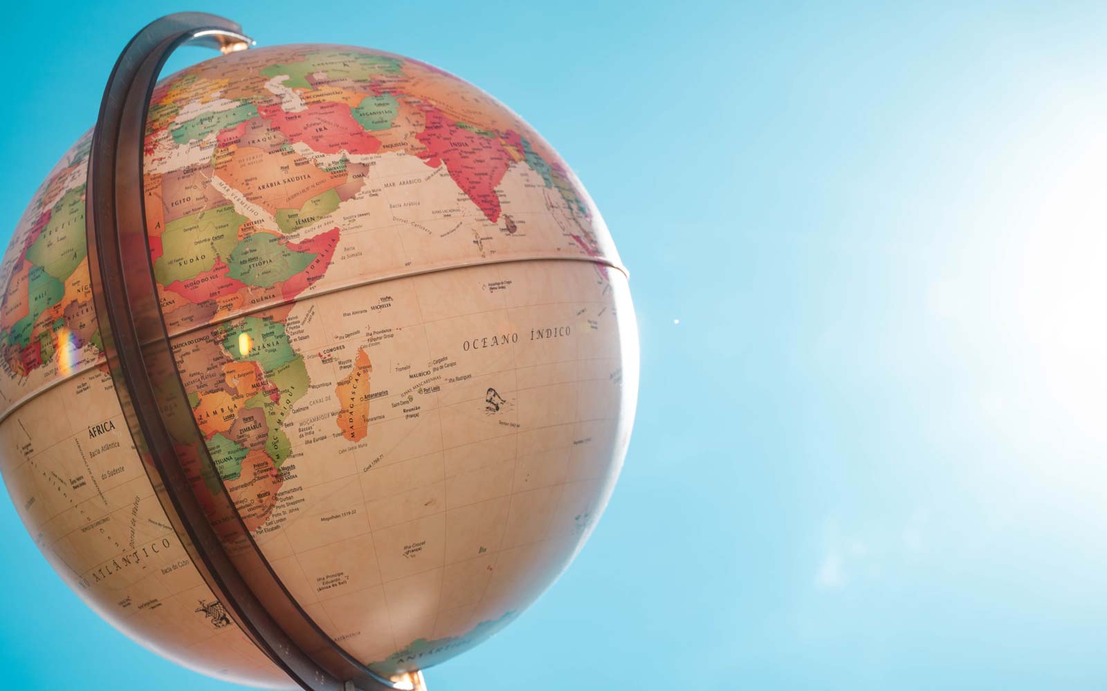 Globe on stand in front of blue, sunny sky