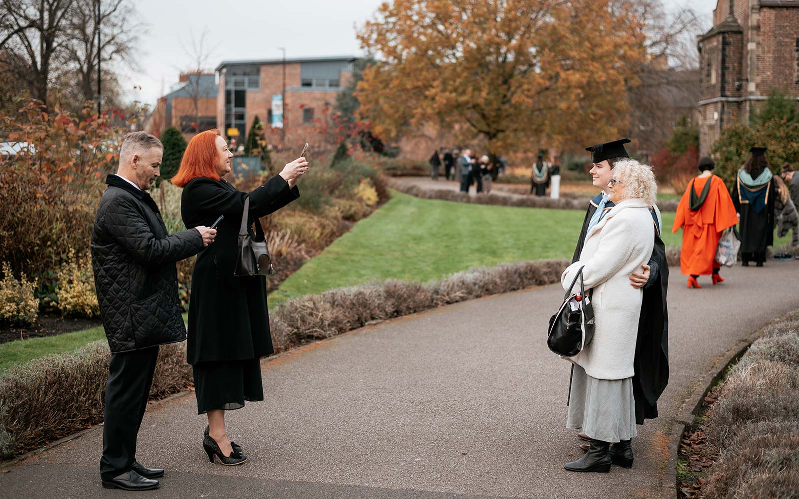Parents taking photos of graduating child and grandparent