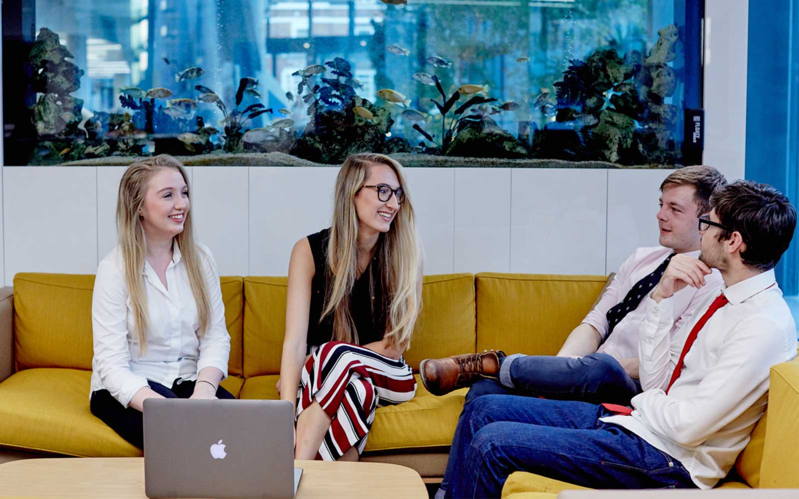 4 students sitting on a couch talking