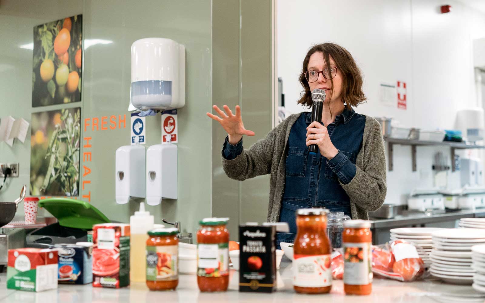 Staff member speaking from behind food preparation counter at Living Lab event