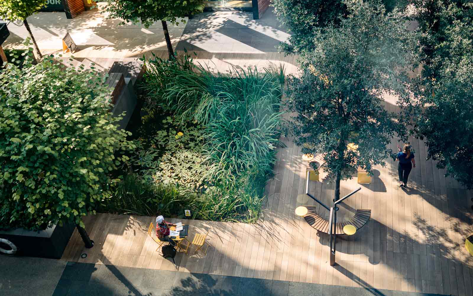A student sitting at a table in a green space on campus.