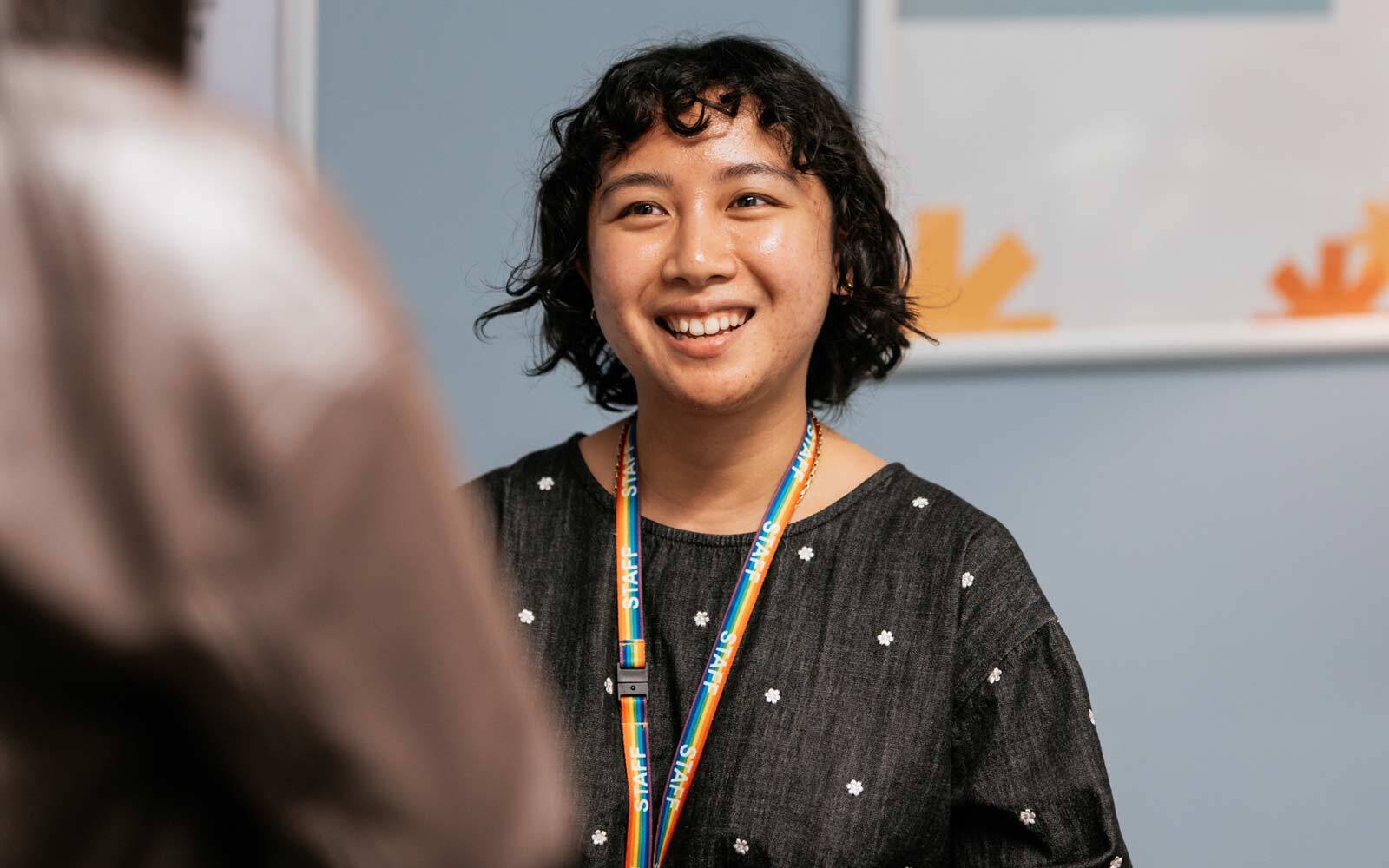 A staff member smiling and listening to someone.