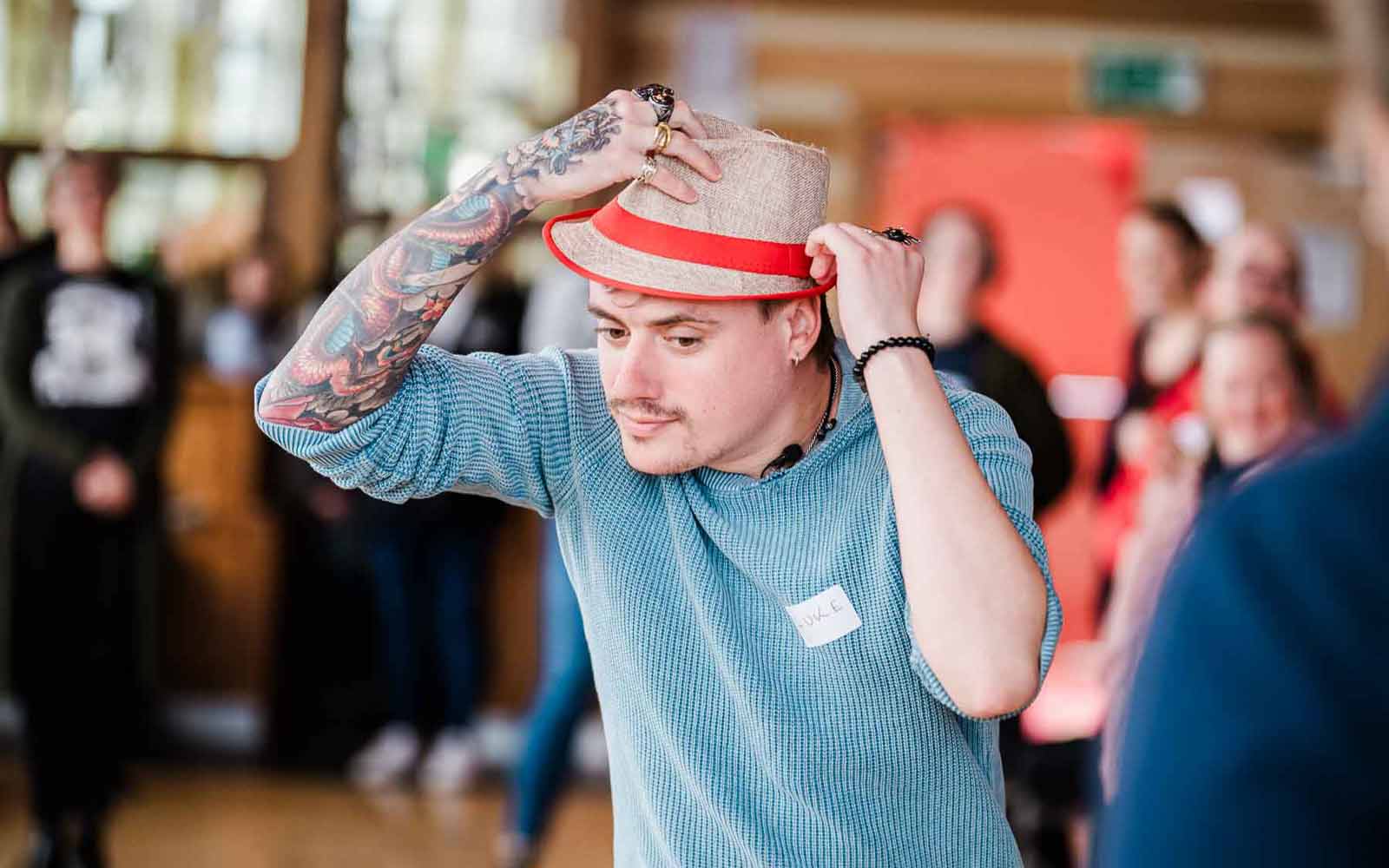 An individual holding a hat on his head