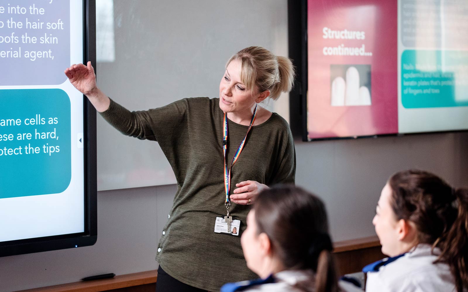 Nursing students listening to tutor explaining powerpoint slide