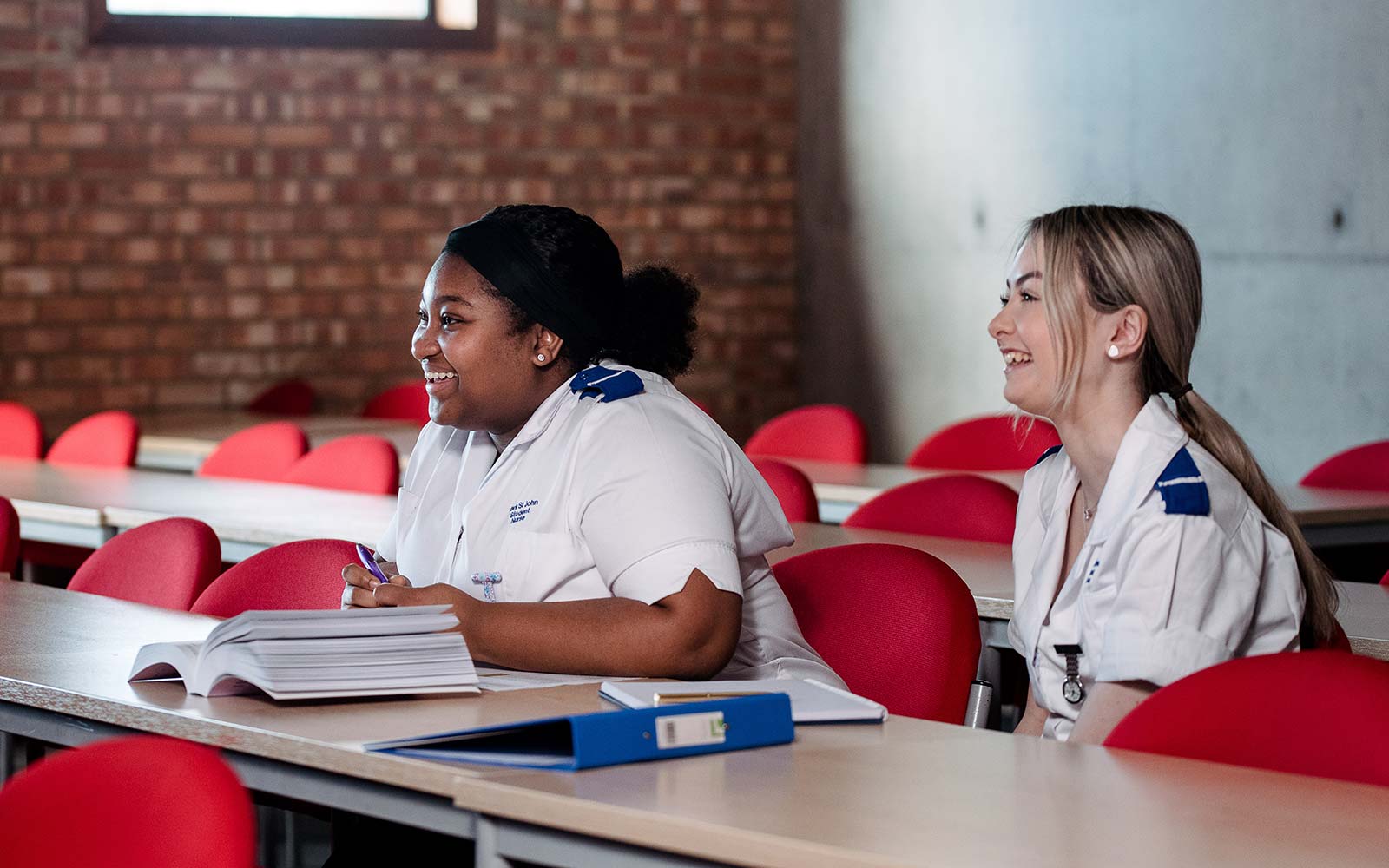 Nursing students in a lecture with books on the tables in front of them.