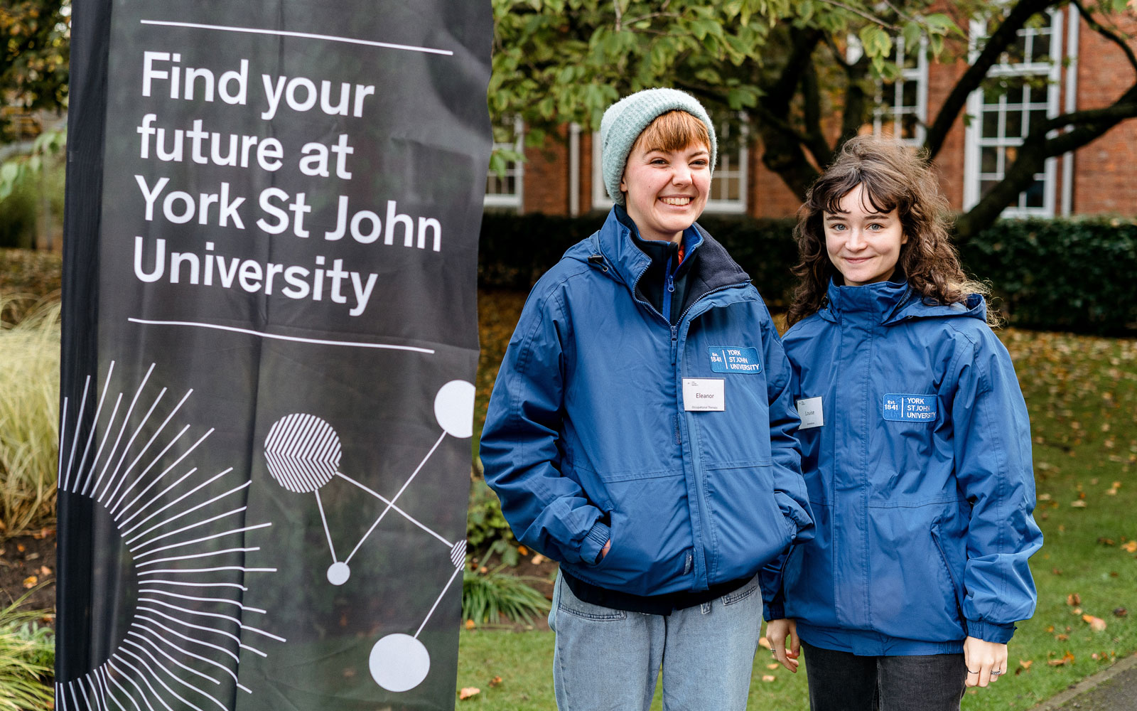 Two Student Ambassadors stood by Open Day signage on campus