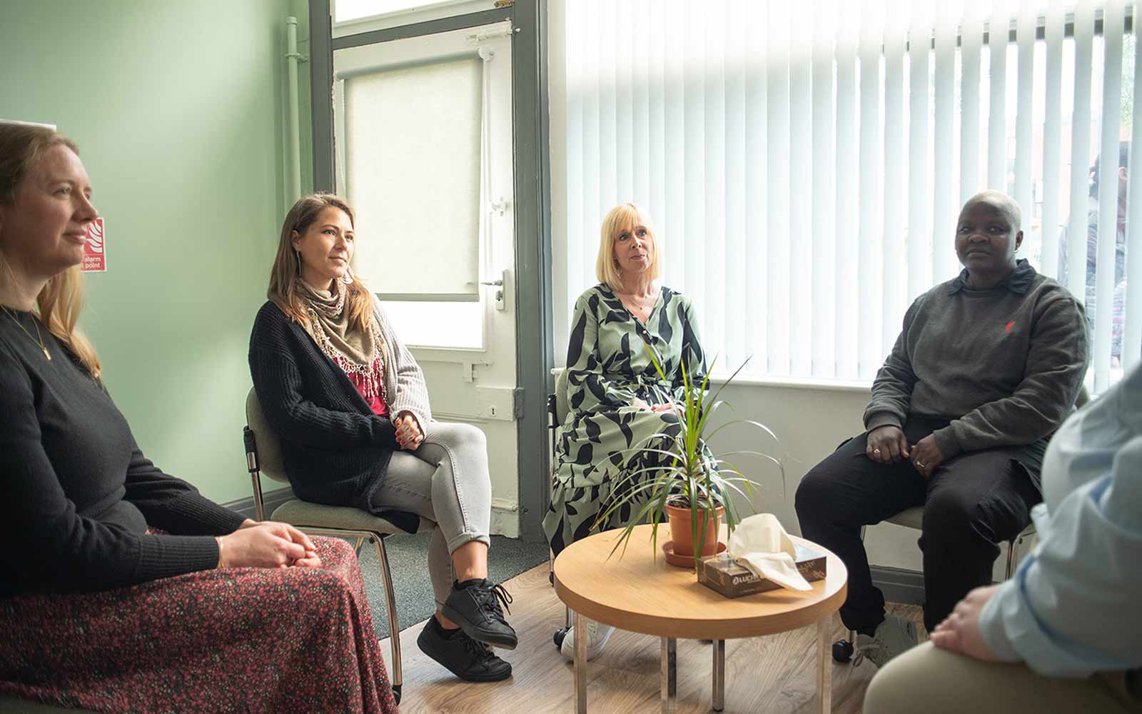 Four people sat around a coffee table having a discussion