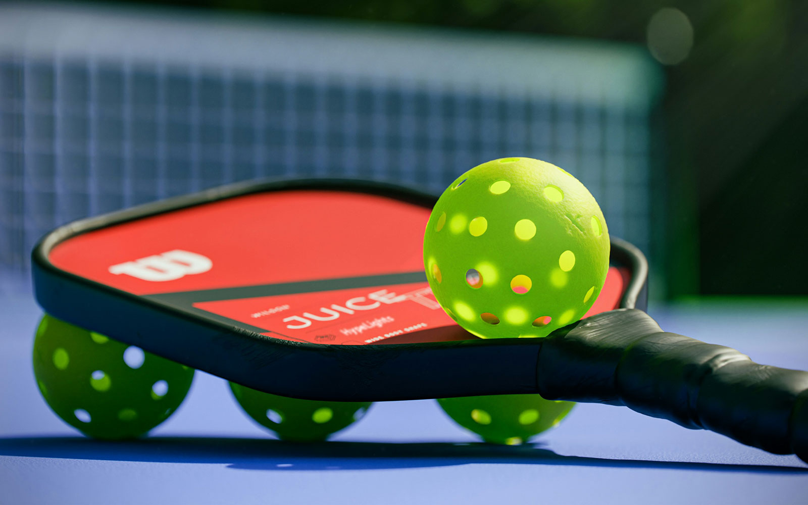 Pickleball bat and ball on court floor