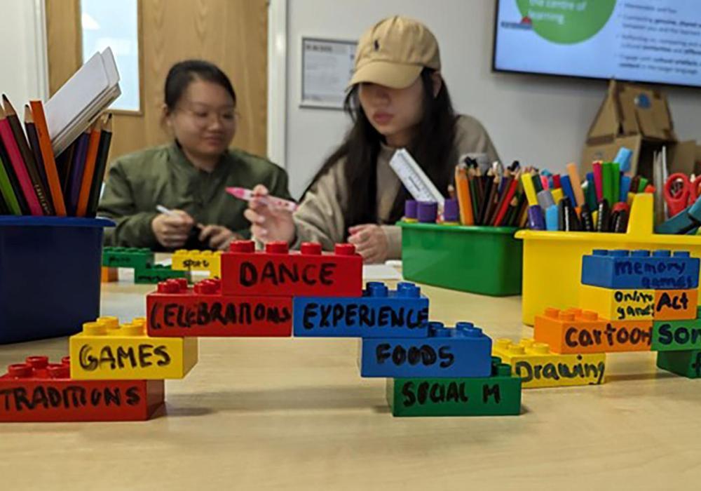 Community Language School volunteers building bridge out of coloured bricks