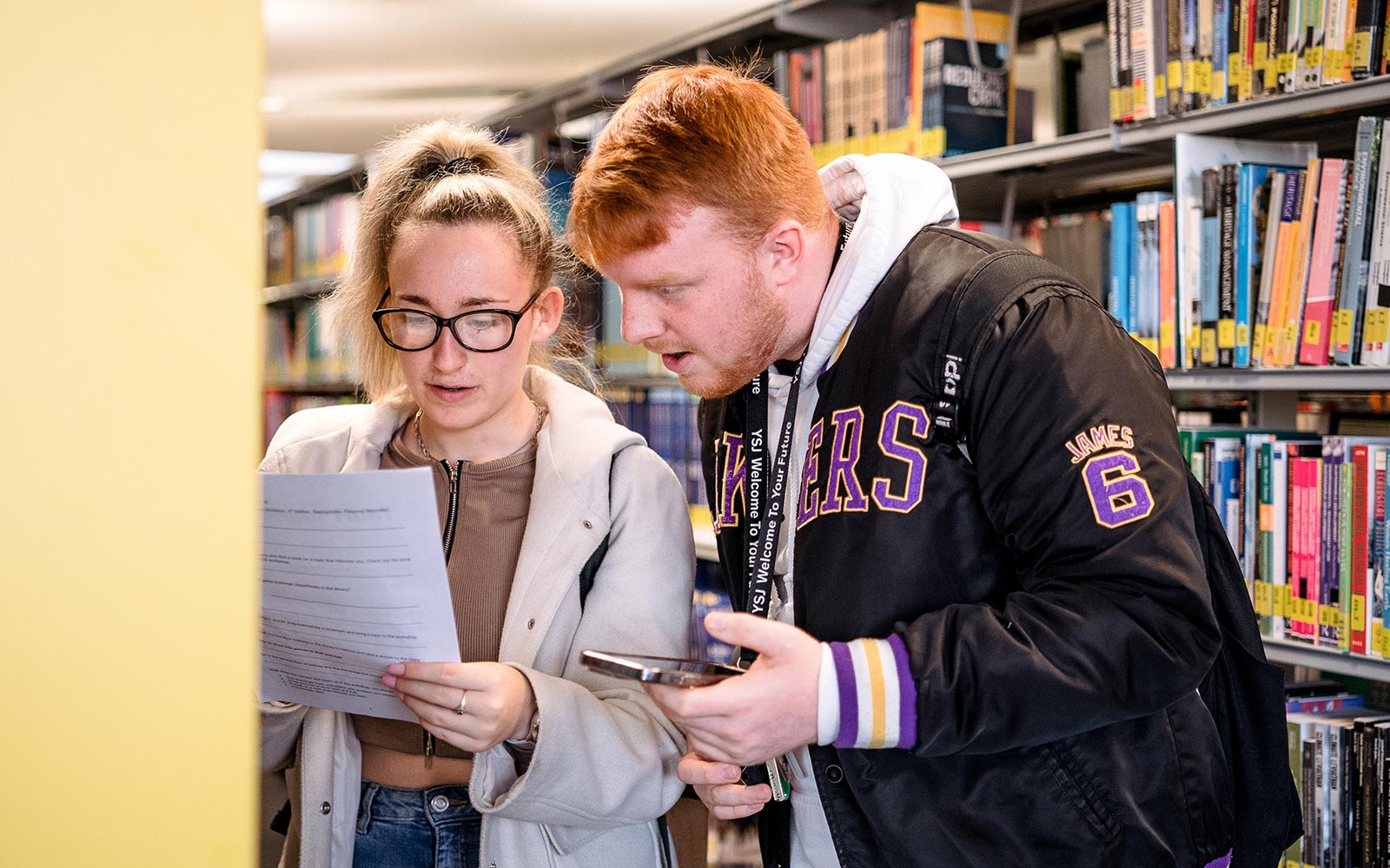 Sociology students looking at paper in Library