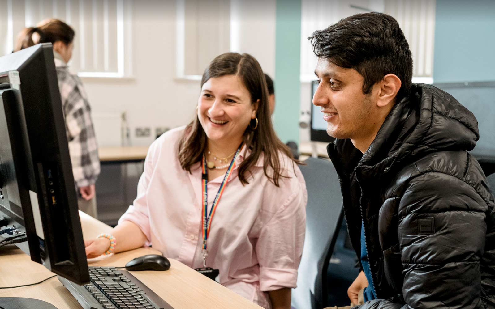 A member of staff and a student work together at a computer.