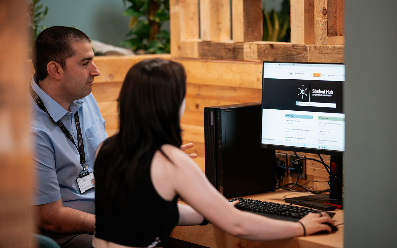 Staff member helping student to access Student Hub portal on computer in Student Hub