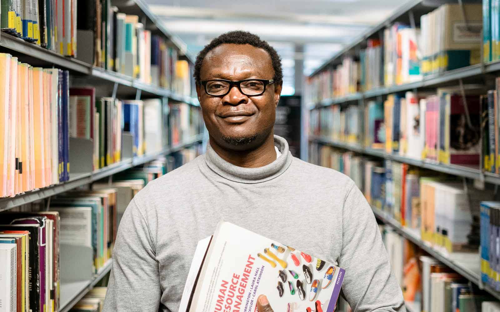 A student holding Human Resource Management textbooks.