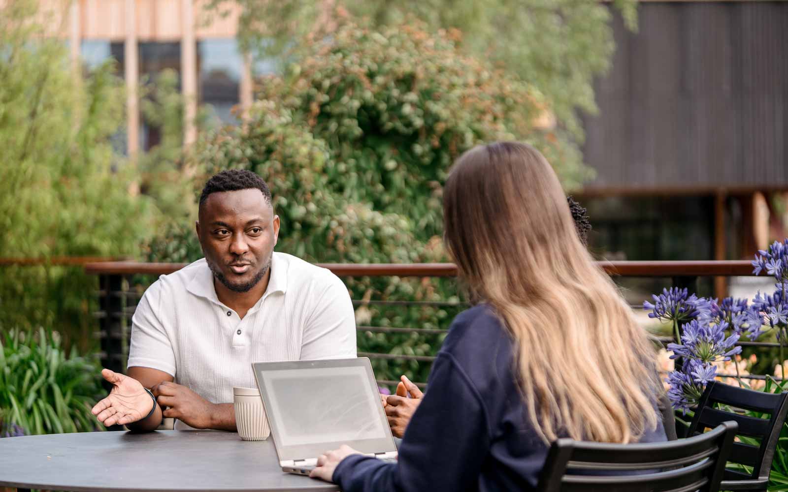 Two students sitting together outside, talking and studying.