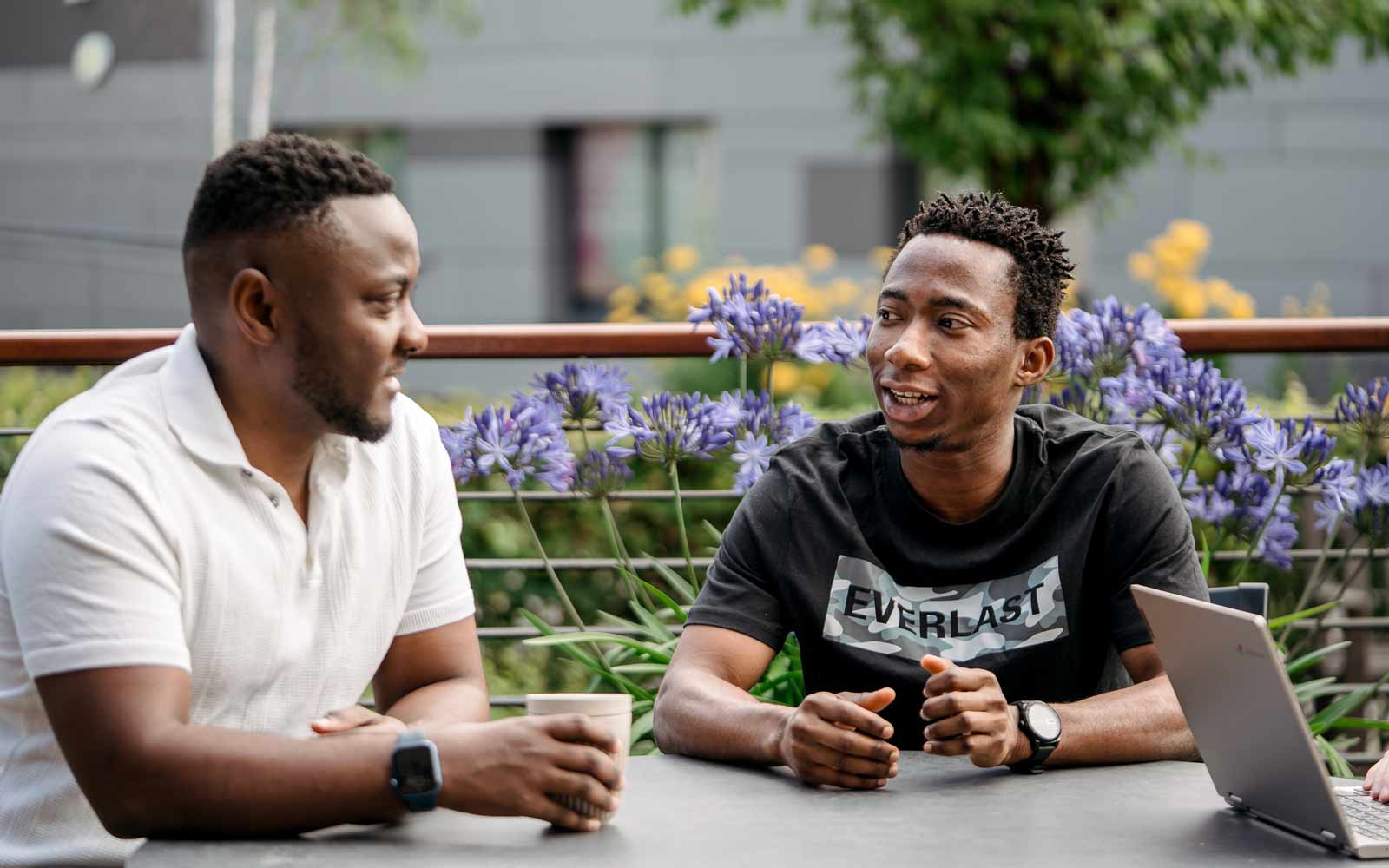 Two students sat at a table outside on campus.