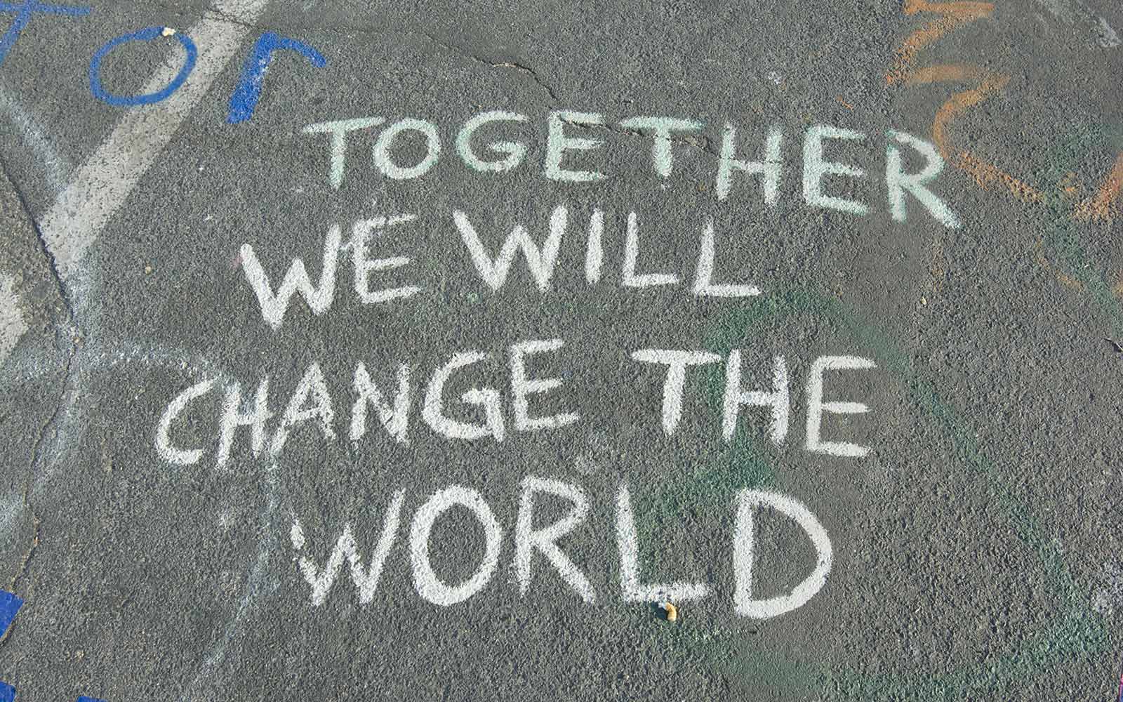 Together we will change the world written in white chalk on pavement