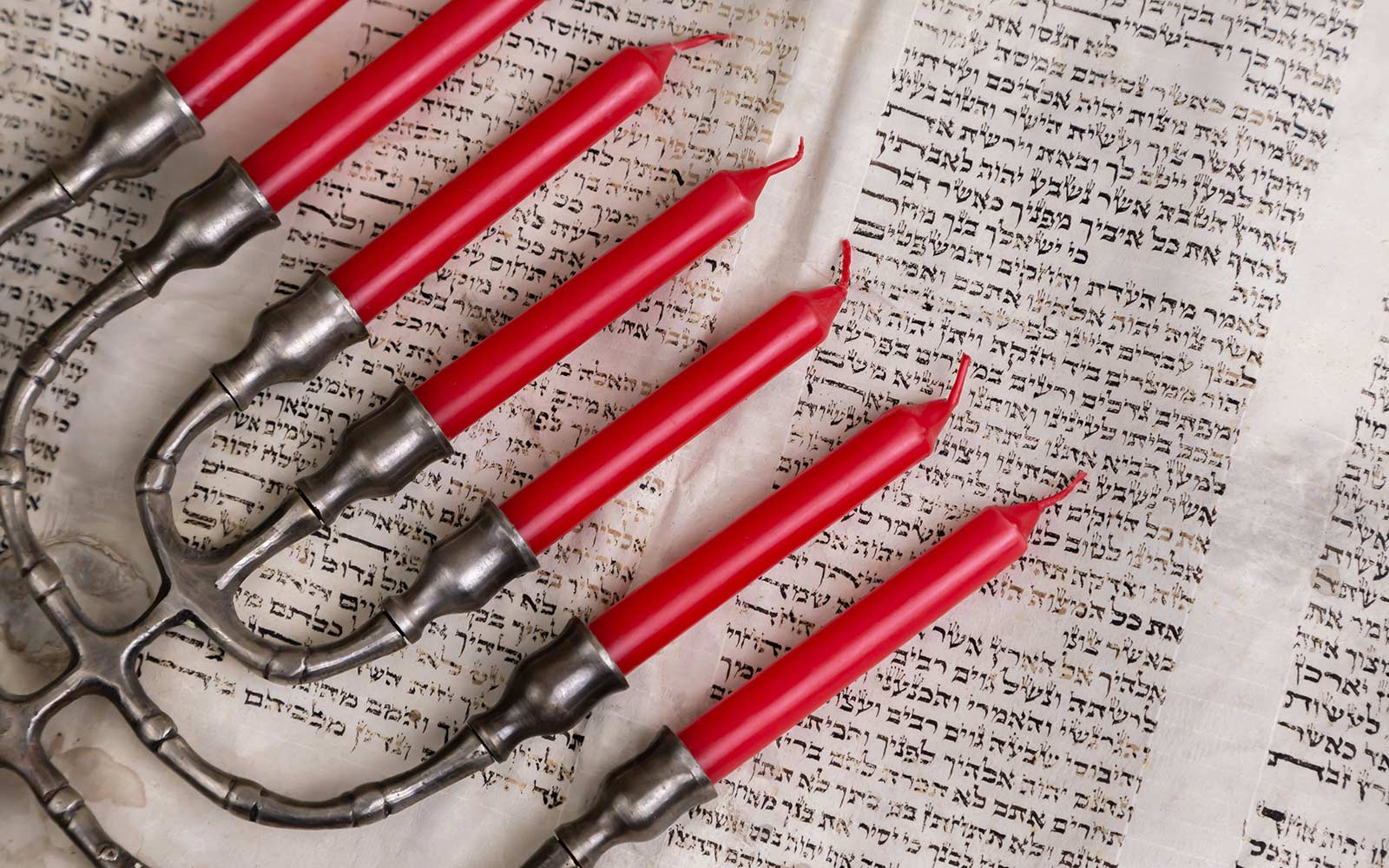 A menorah lying on top of a page from the Torah
