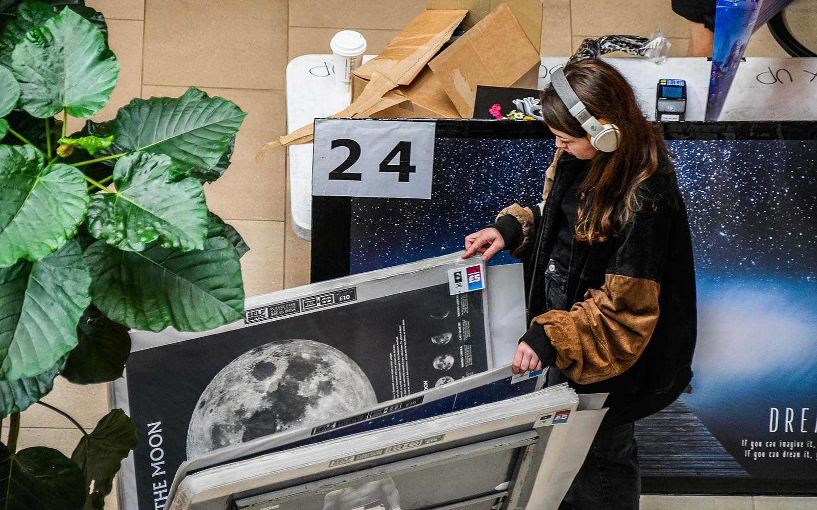 Student browsing through posters, wearing headphones