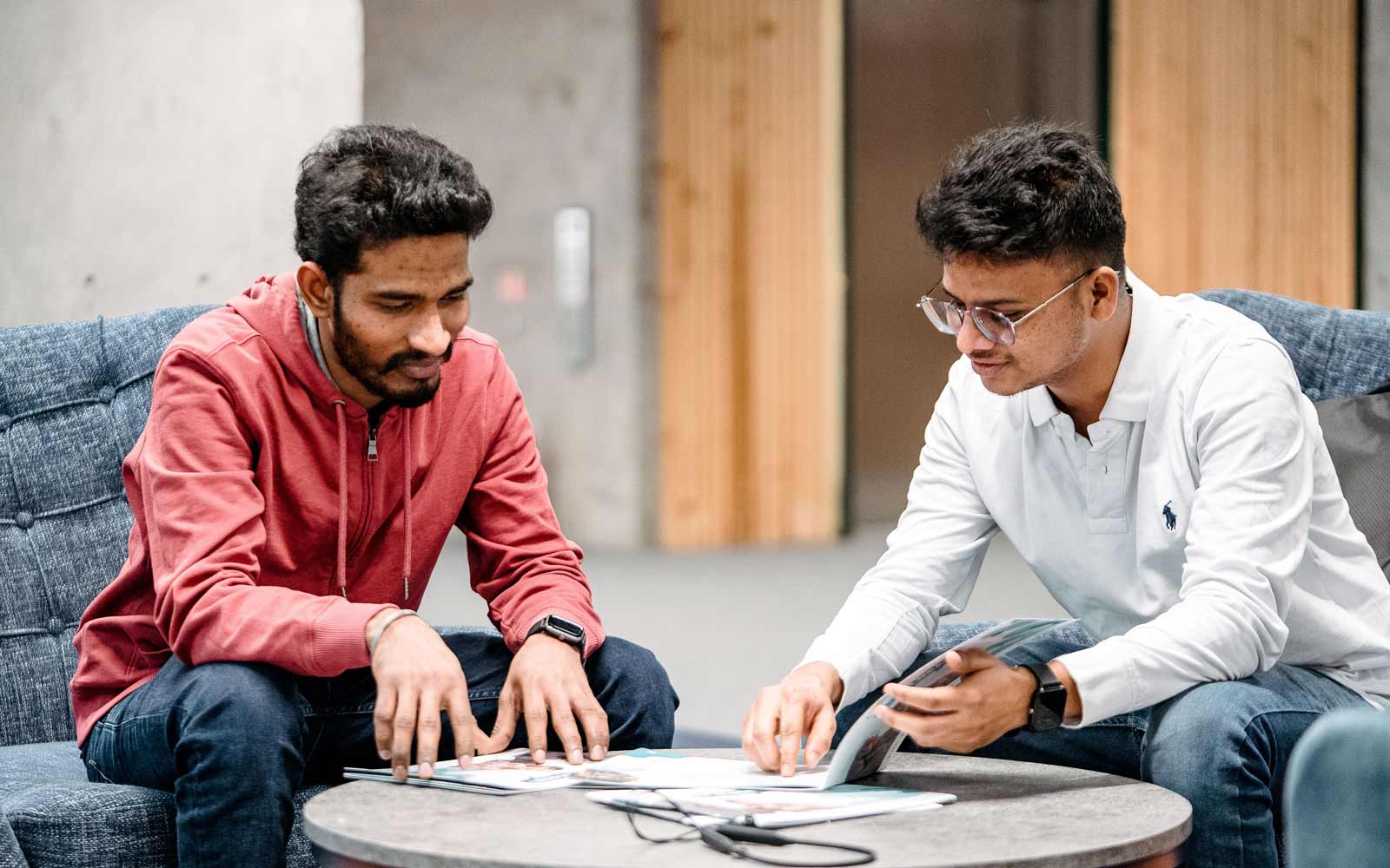 Students sat in comfy chairs at a table looking at leaflets