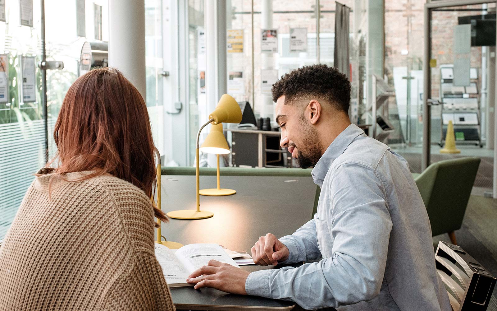 Careers Adviser sitting at table with student looking at leaflet