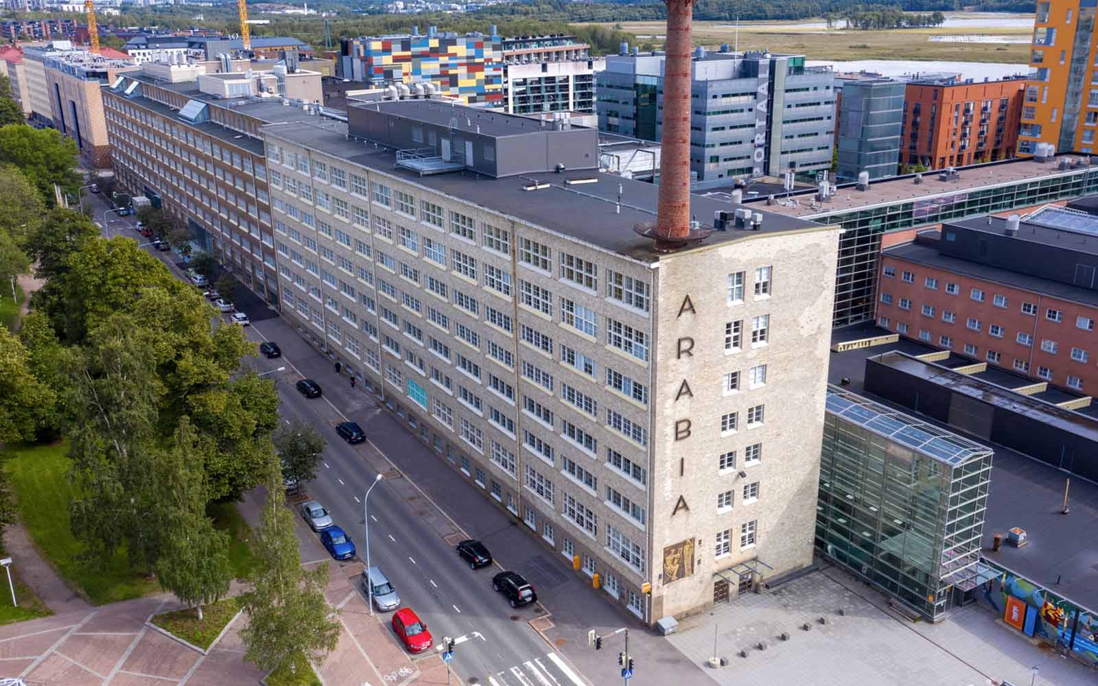 View of converted industrial building on tree-lined street, Helsinki Metropolia University.