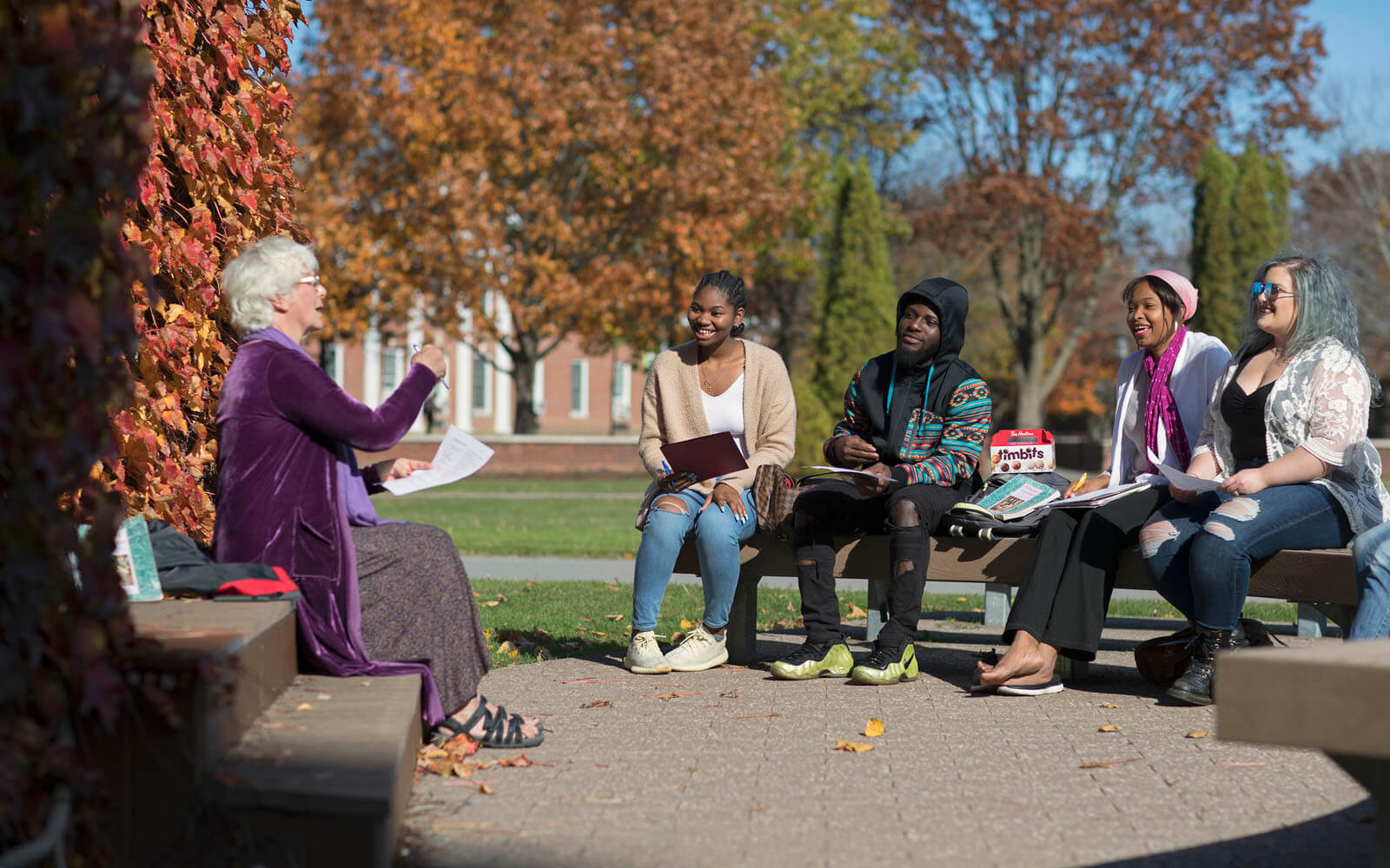 Lecturer and students sat on benches in conversation at State University of New York
