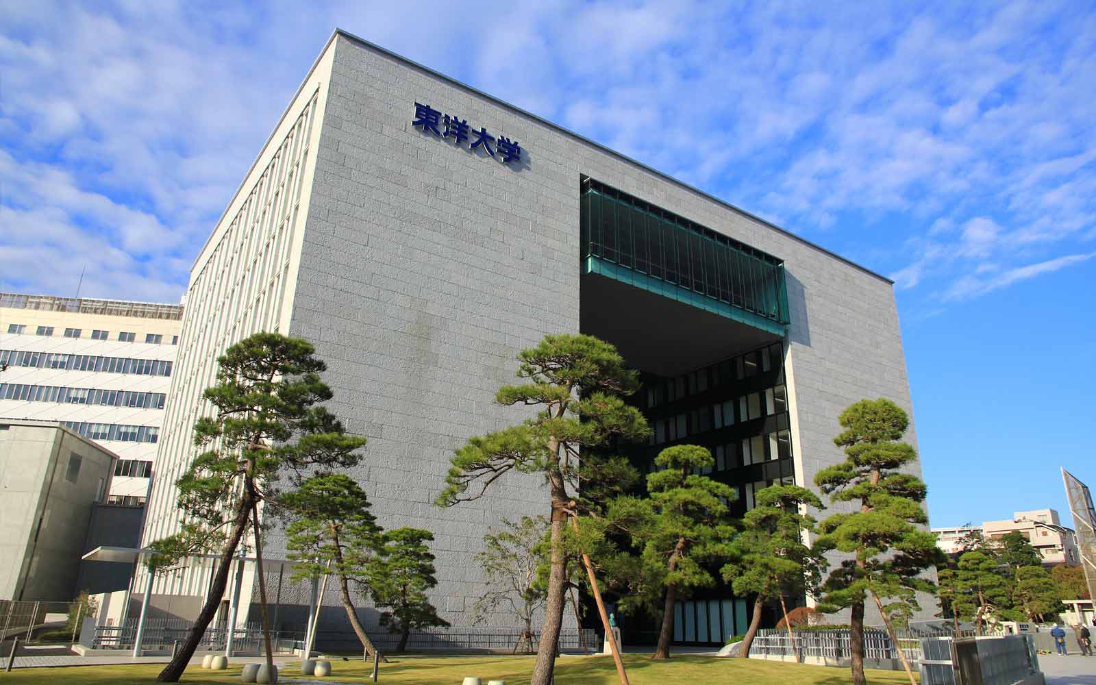 Large modern building surrounded by trees on Toyo University campus.